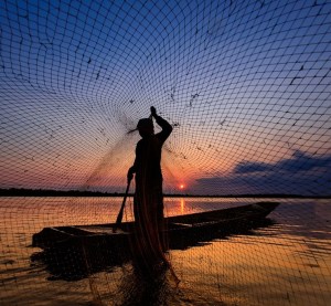 Image of someone fishing and casting a net into the sea.

